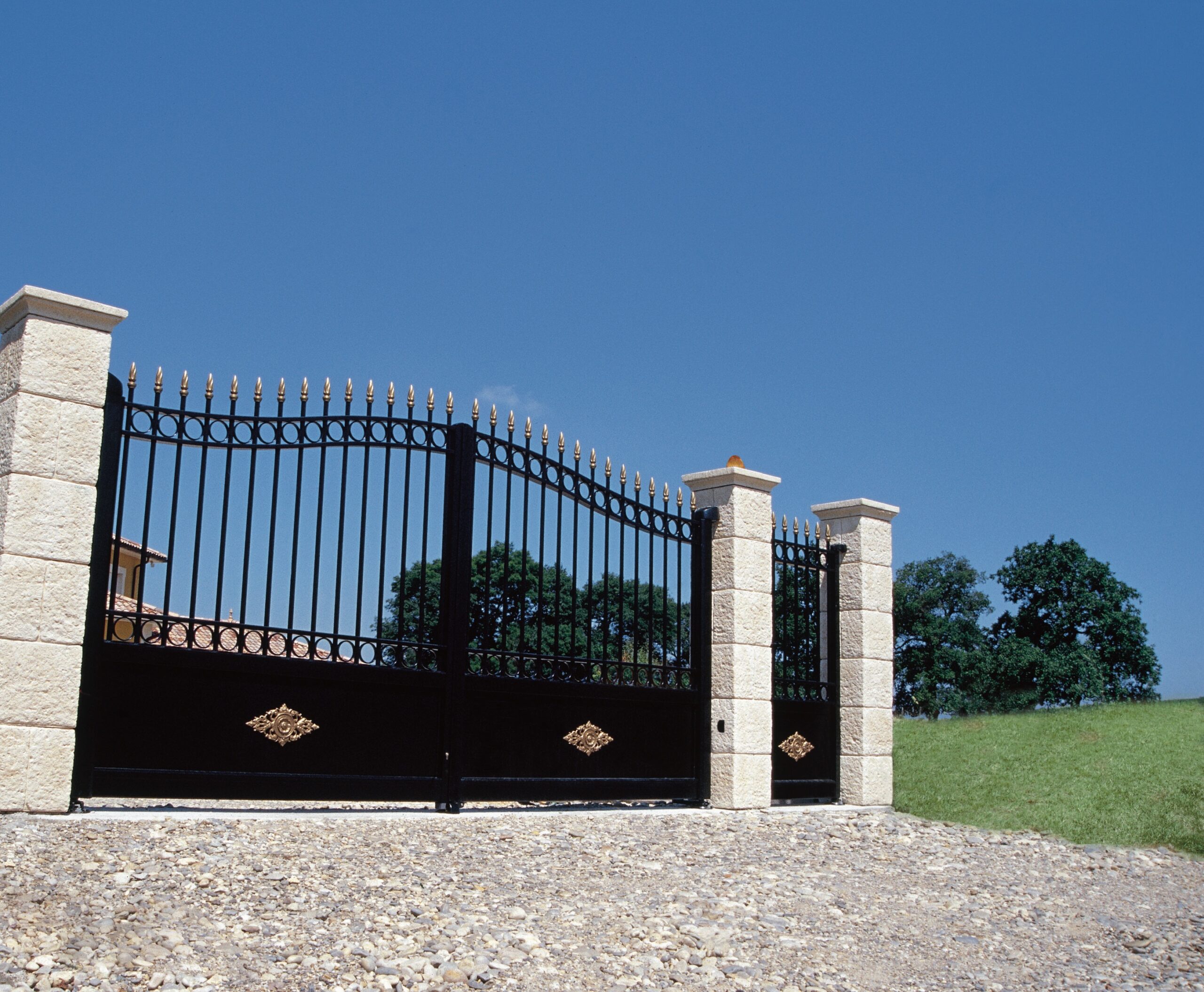 Black and gold sunny wrought iron replica aluminium gates with swing gates and pedestrian gate fixed to white pillars